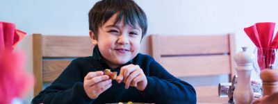 Happy kid eating sunday dinner at home, Child boy having Chirstmas lunch with family.